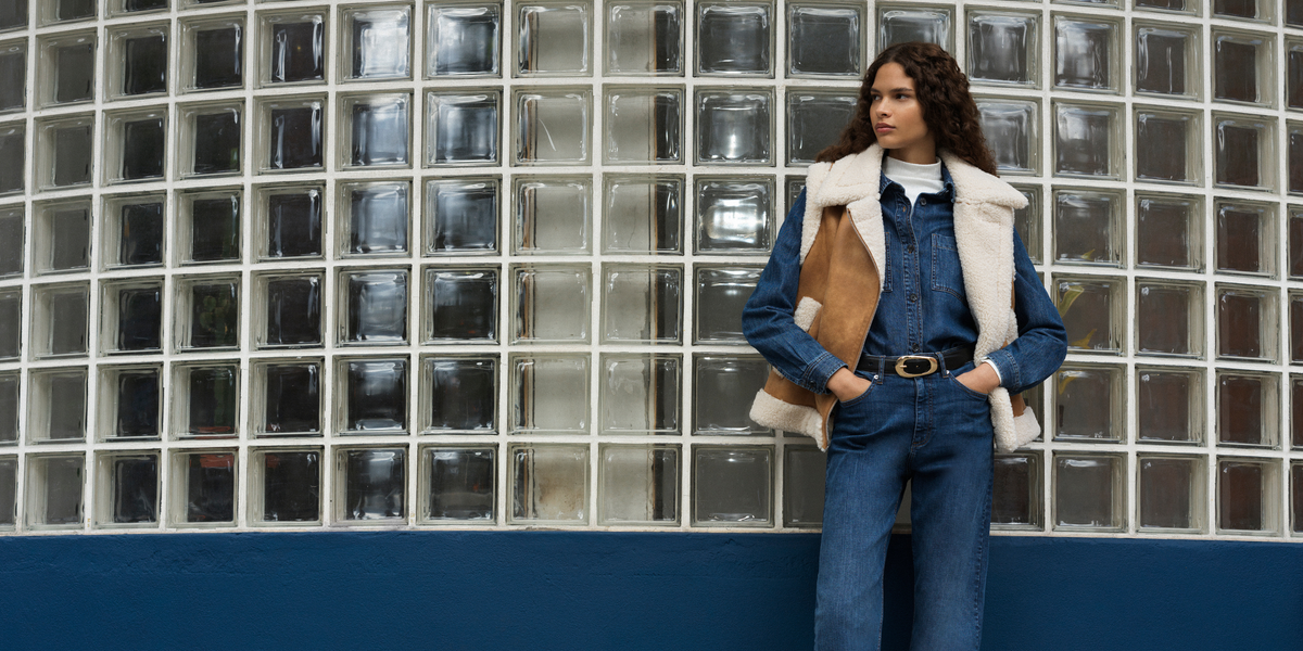 A woman in denim jeans, a denim shirt, and a suedette gilet creates a stylish look, perfect for autumn outfit ideas.