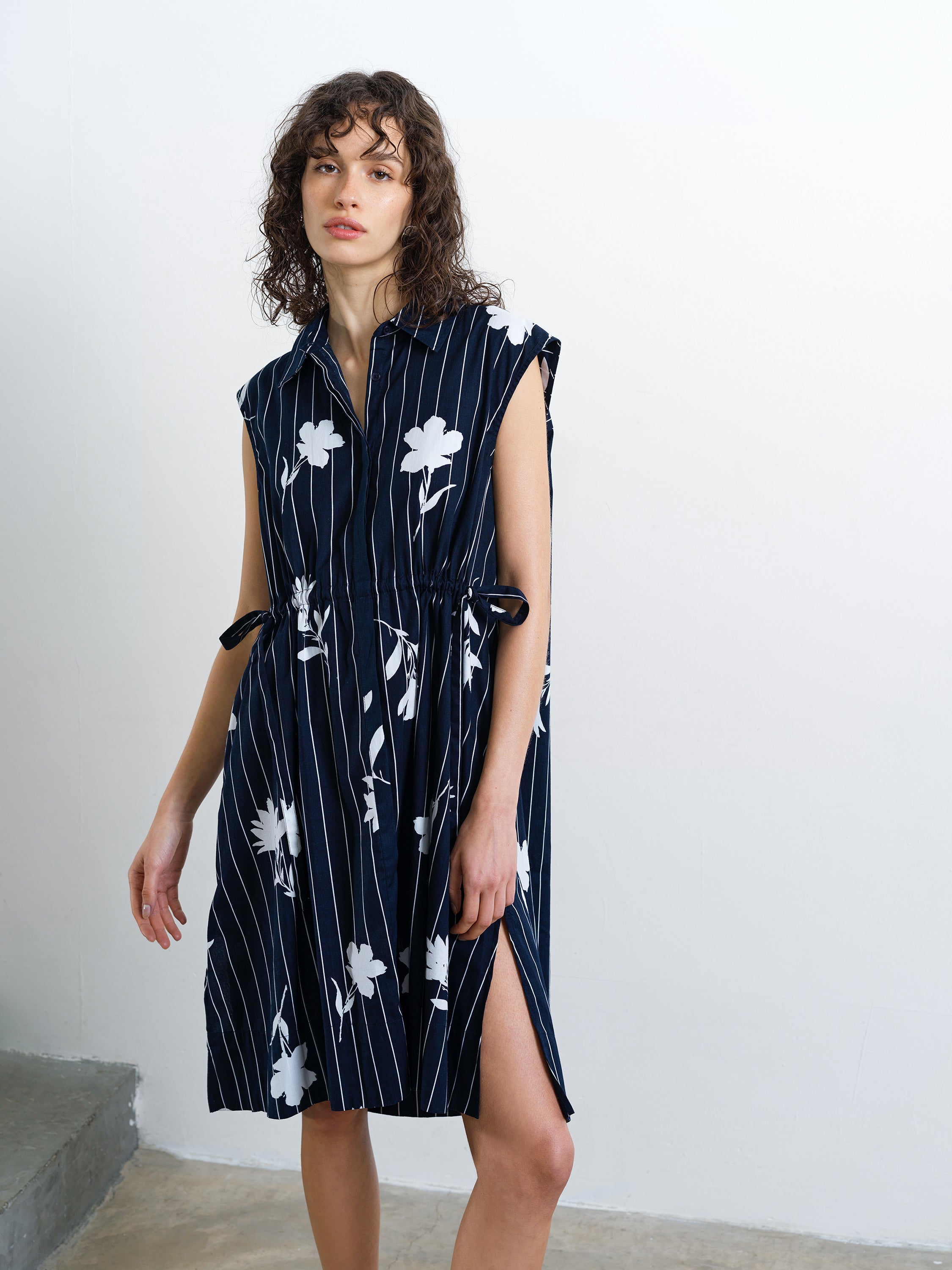 Woman wearing a sleeveless floral pinstripe navy and white dress