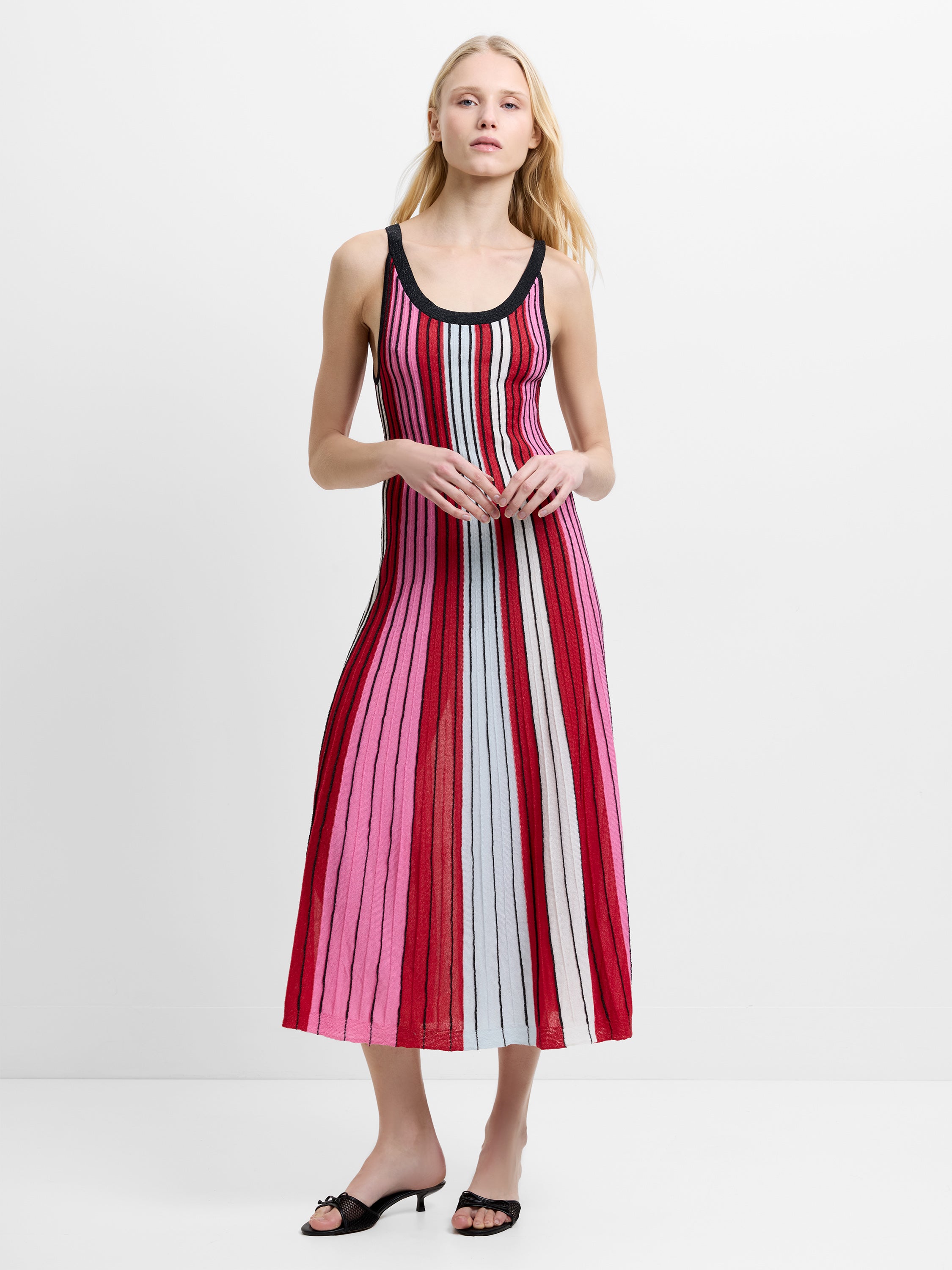 Woman wearing a pink, red and white striped, textured knitted midi dress with straps and a scoop neckline