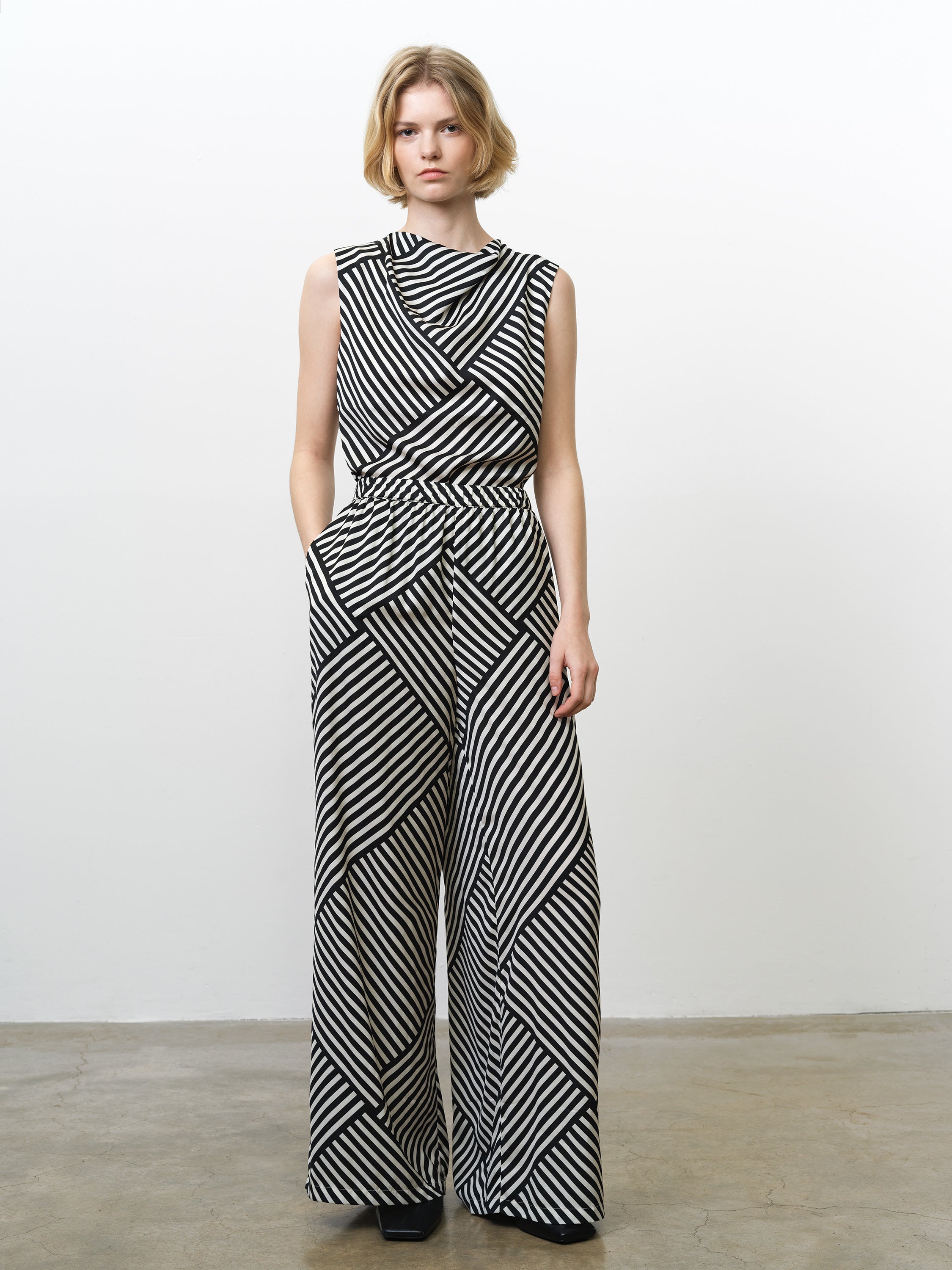 Woman wearing high waisted wide leg trousers, in a black and white asymmetric striped print