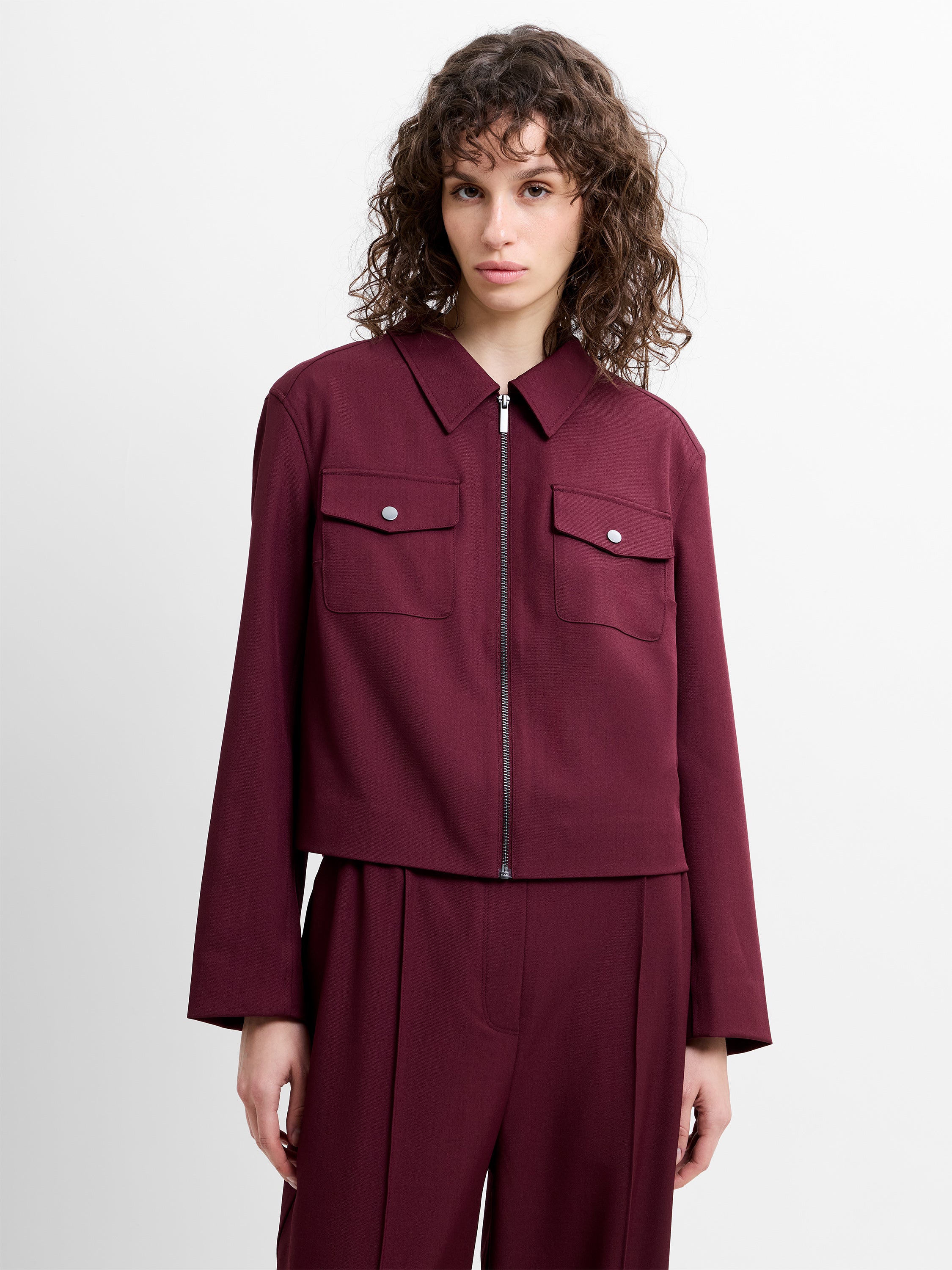 Woman wearing a burgundy collared jacket with matching burgundy trousers