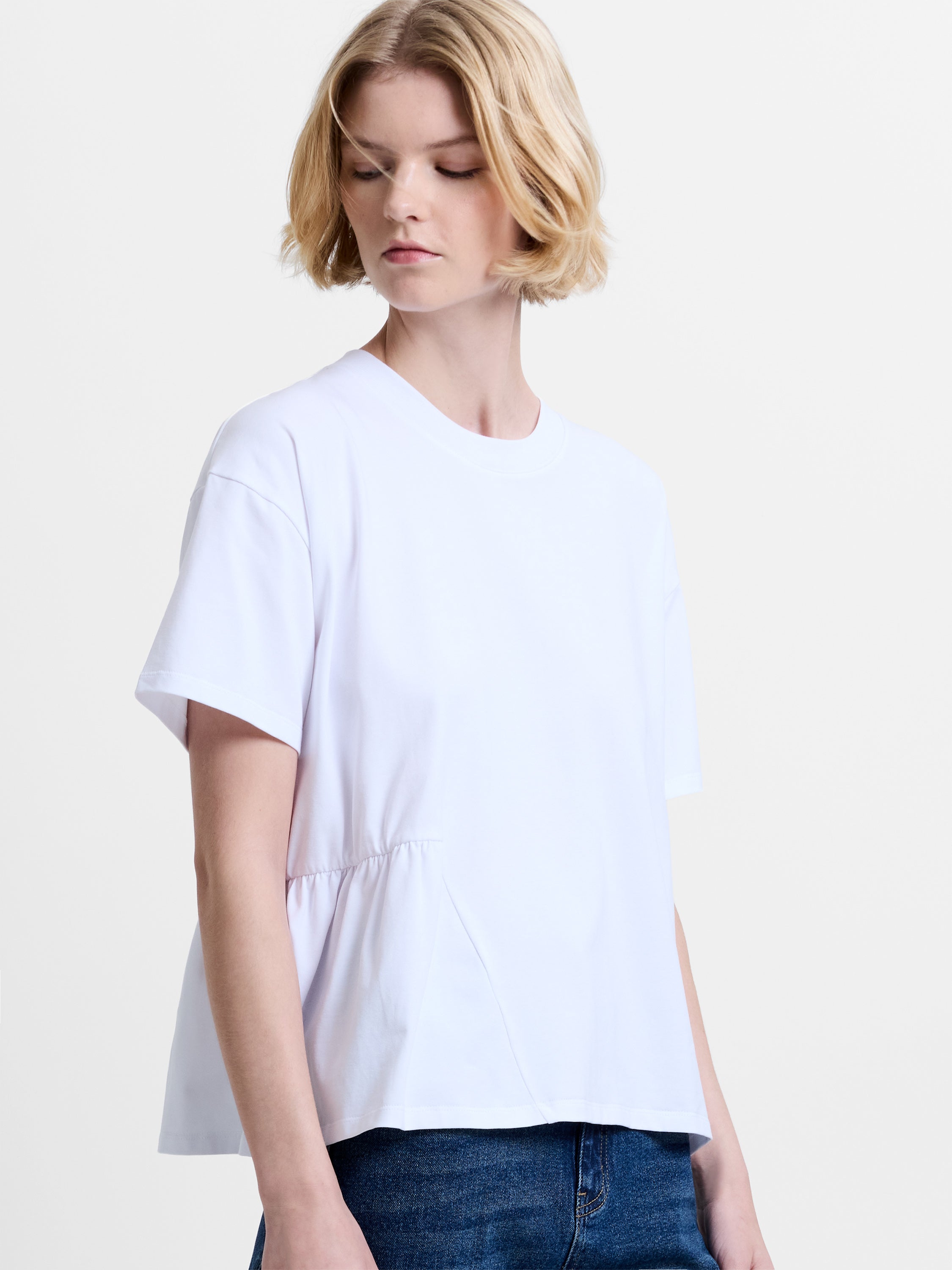 Woman wearing a white short sleeve T-shirt with a round neckline and asymmetric ruching detailing