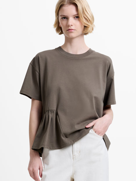 Woman wearing a short sleeve khaki T-shirt with a round neckline and asymmetric ruching detailing