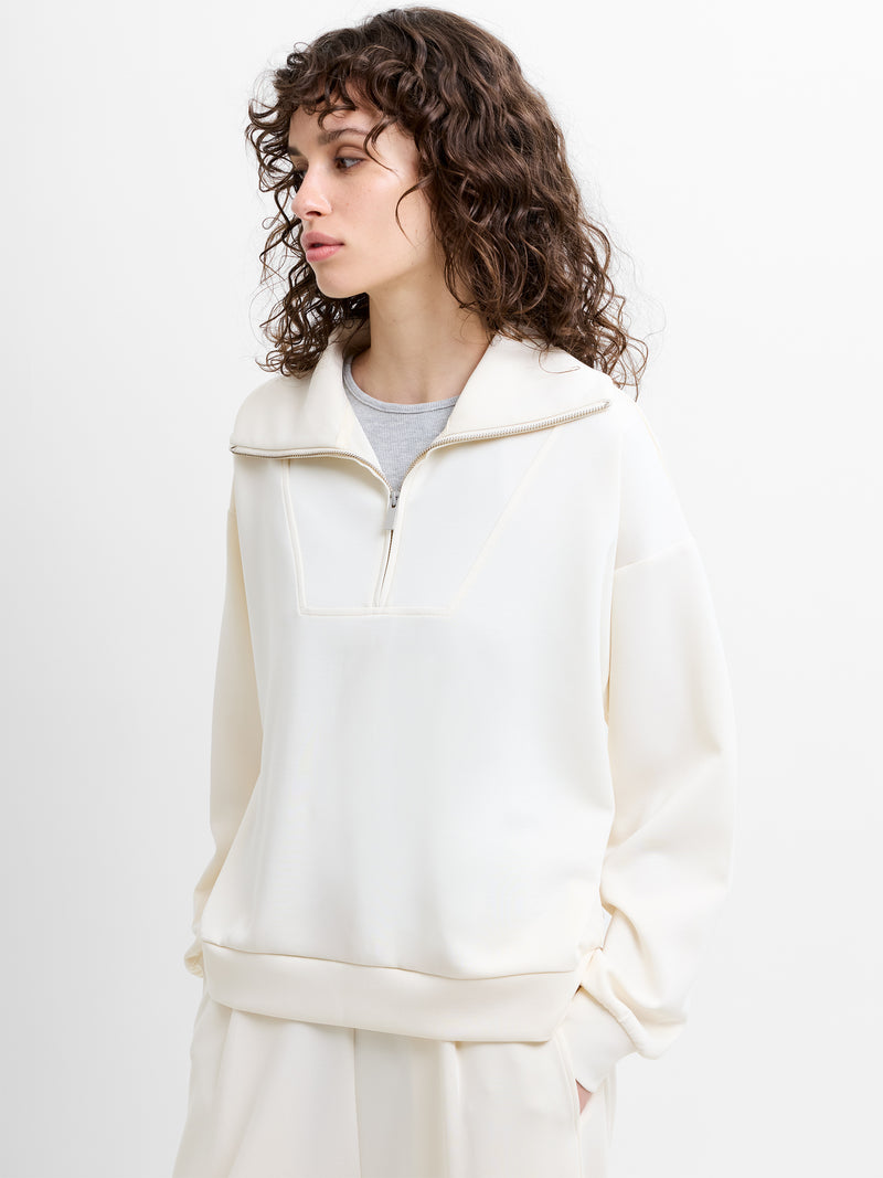 Woman wearing a white sweatshirt with zip fastening