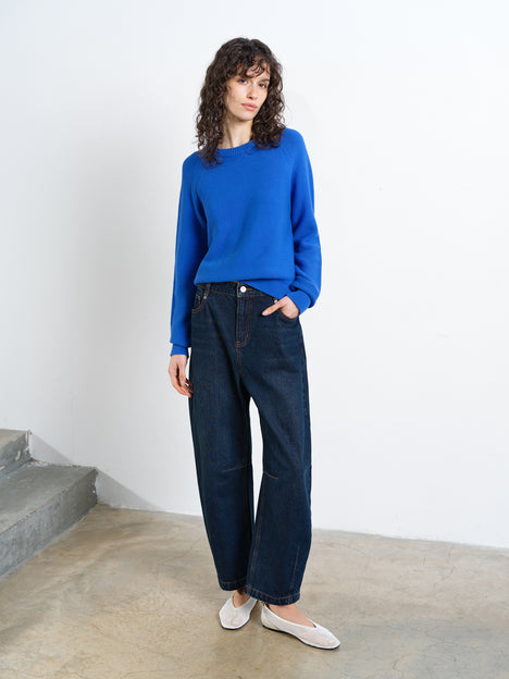 Woman wearing a blue long sleeve crew neck jumper, with a ribbed hem and ribbed cuffs